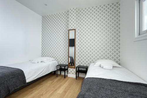 sypialnia z dwoma łóżkami i lustrem w obiekcie Superb Large and New 4bds Flat - Heart of Paris 10 w Paryżu