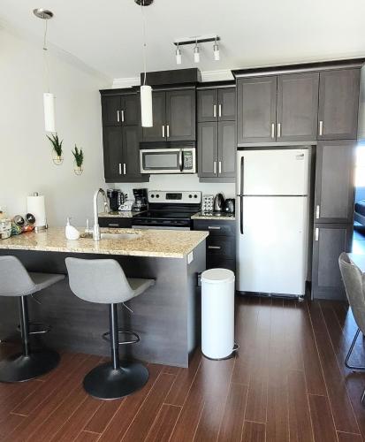 Una cocina con un refrigerador blanco y una encimera. en Condo 202 Le Champlain vue sur la montagne, ski, vélo, piscine !, en Bromont