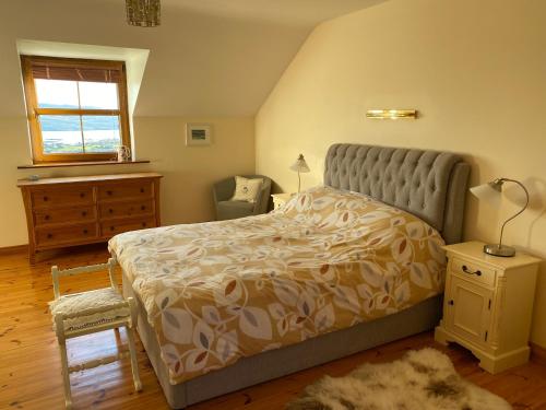 a bedroom with a bed and a chair and a window at Stunning hideaway on the Wild Atlantic Way in Knocknaud