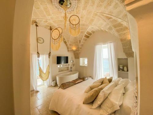 a bedroom with a large white bed with a couch at Apulia Charming Suites - Casa Rossa Suite Perla e Suite Corallo in Savelletri di Fasano