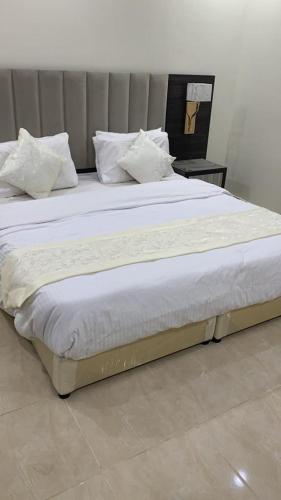 1 cama grande con sábanas blancas y almohadas. en Reef 18 by Al Azmy en Riad