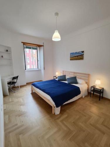 a bedroom with a large bed with a blue blanket at [WHITE & WOOD house in Rome] in Rome
