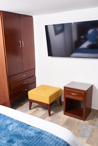 a bedroom with a tv and a table and a stool at Hotel Mansión Barichara in Barichara