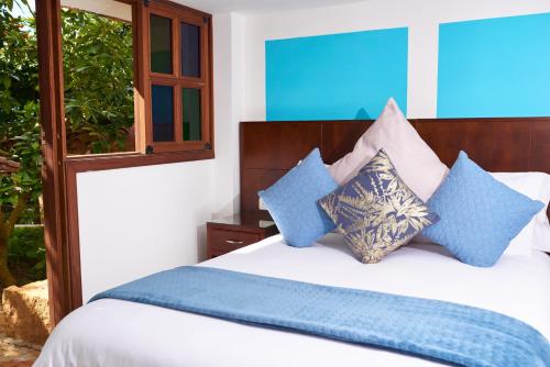 a bedroom with a white bed with blue pillows at Hotel Mansión Barichara in Barichara