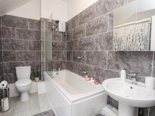 a bathroom with a tub and a toilet and a sink at Llys Mair in Bala