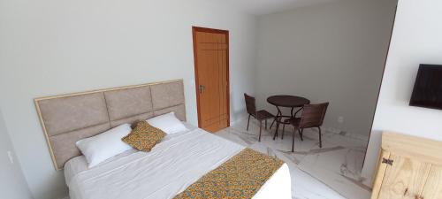 a bedroom with a bed and a table and chairs at Pousada e Chale Porto Paraiso in Porto Seguro
