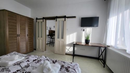 a bedroom with a bed and a desk and a television at Relax Apartments Sárvár A1 in Sárvár