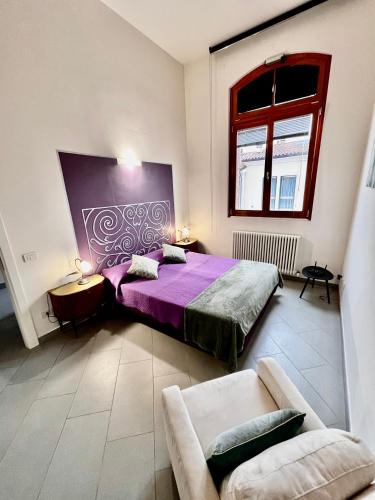 a bedroom with a purple bed and a couch at Ca Mimì in centro in Ravenna