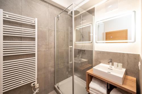 La salle de bains est pourvue d'un lavabo et d'une douche. dans l'établissement Kuckuck Hinterthal - Appartements, à Hinterthal