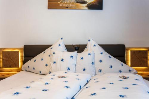 a bed with white sheets and blue flowers on it at Pension Hauser in Sankt Jakob in Haus