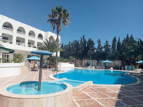 una piscina con una palmera y un edificio en Residence Royal - Deluxe en Hammamet Sud