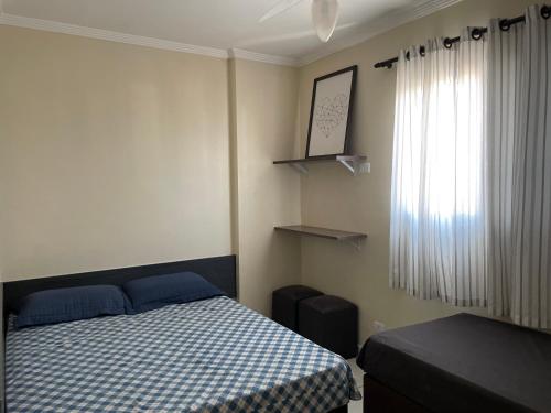 a small bedroom with a bed and a window at Apto com Piscina e Churrasqueira in Praia Grande