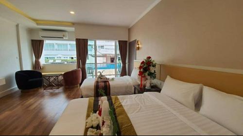 a hotel room with two beds and a table and a desk at Swan Lake Hotel Sattahip in Sattahip