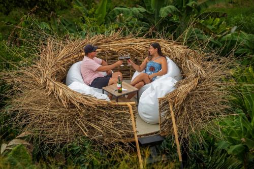 Ein Mann und eine Frau sitzen in einem Strohkreis mit Getränken in der Unterkunft Eco Hotel La Colina Mirador in Quimbaya