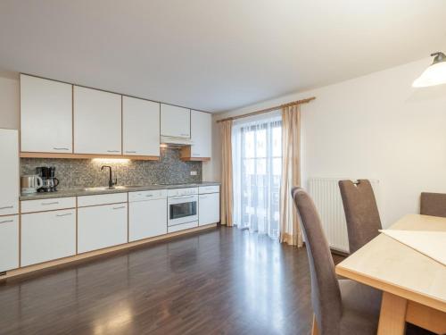 a kitchen with white cabinets and a table with chairs at Haus Durchegg OG in Wagrain