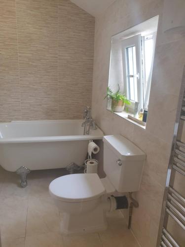 a bathroom with a toilet and a tub and a sink at Resthaven Cottage in Mablethorpe