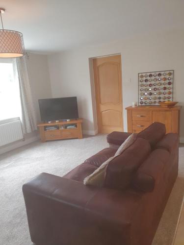 a living room with a brown couch and a flat screen tv at Resthaven Cottage in Mablethorpe