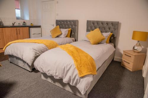Duas camas num quarto com almofadas amarelas. em Bv Comfy Basement 2 At Manningham Bradford em Bradford