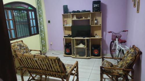 a living room with two chairs and a television at Recanto dos Jardim's Arraial do Cabo in Arraial do Cabo