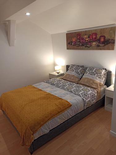 ein Schlafzimmer mit einem Bett und einem Gemälde an der Wand in der Unterkunft La tranquillité in Vaujours