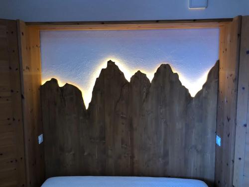 a bedroom with a wooden wall with a picture of mountains at Paradise Dolomiti flat in Falcade