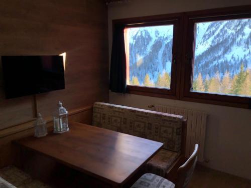 a dining room with a wooden table and two windows at Paradise Dolomiti flat in Falcade