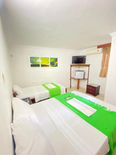 a room with two beds and a television at Hotel La Guajira in Ríohacha