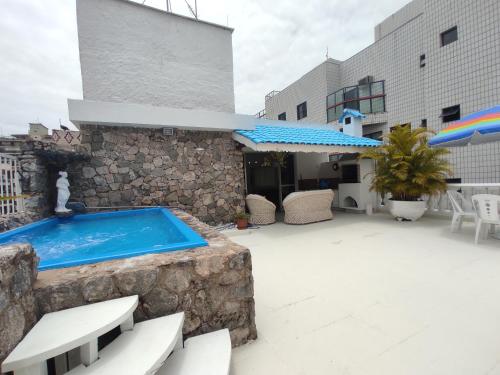 a patio with a swimming pool next to a building at Cobertura Enseada Guarujá - 250 metros da praia in Guarujá