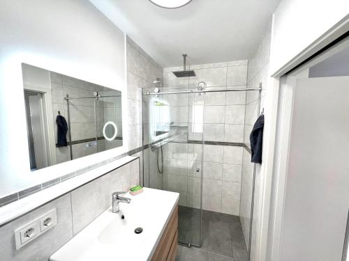 a white bathroom with a sink and a shower at Ferienwohnung Brochenzell - nahe Ravensburger Spieleland in Meckenbeuren