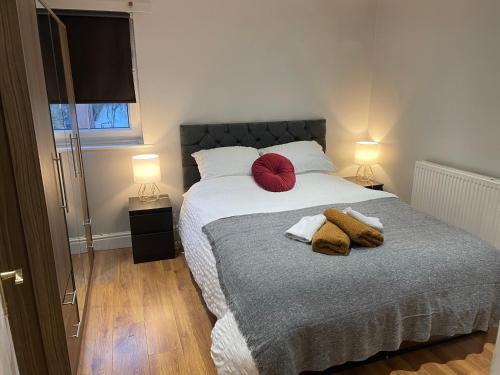 a bedroom with a bed with two red pillows on it at 2 Bedroom Apartment Chiswick Park Tube Station in London