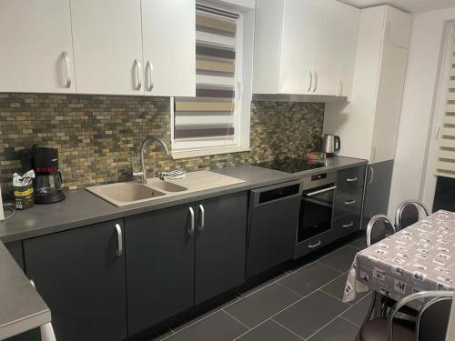 a kitchen with black and white cabinets and a sink at Apartament Cluj in Floreşti