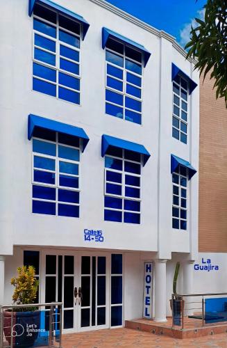 duży biały budynek z niebieskimi oknami w obiekcie Hotel La Guajira w mieście Ríohacha