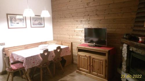 ein Esszimmer mit einem Tisch und einem TV in der Unterkunft La Casa Rossa - Presolana in Castione della Presolana