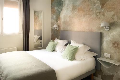 a bedroom with a large white bed with green pillows at Le Magnan in Avignon