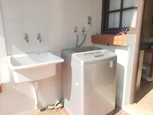 baño pequeño con lavabo y lavadora en Hostal Palamas, en Tarija