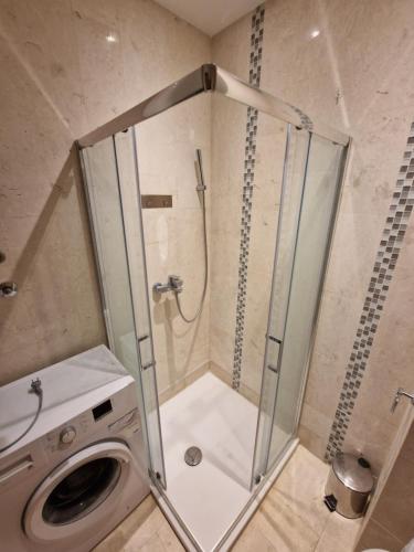 een badkamer met een douche en een wasmachine bij AS Apartments Rafailovici in Rafailovici
