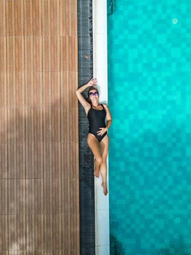 a woman in a black bathing suit sitting on the side of a swimming pool at NIVADOO RESORT SIGIRIYA in Sigiriya