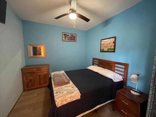 1 dormitorio con cama y pared azul en VILLAS MARCO POLO, en Panajachel