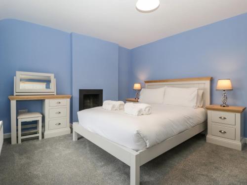 a blue bedroom with a bed with two towels on it at Granary Cottage in Warminster