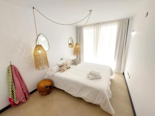 a bedroom with a white bed and a large window at Beach Suite Cotillo by Sea You There Fuerteventura in El Cotillo