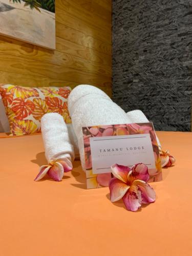 a hotel room with towels and flowers on a bed at TAMANU LODGE in Punaauia