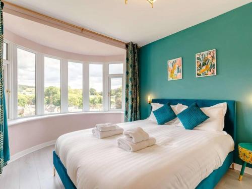 a bedroom with a large bed with blue walls and a window at Dawns House Cromford, Peak District, Hot Tub, for 6 - stunning views in Cromford