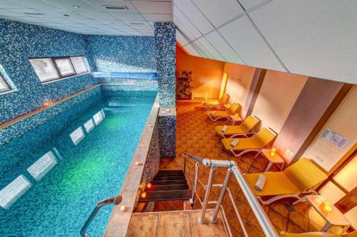 a large swimming pool in a building with yellow chairs at Oak Residence Hotel & Relax in Smolyan