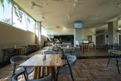 a restaurant with wooden tables and chairs and windows at Hotel Mio Vallarta - Adults Only in Puerto Vallarta