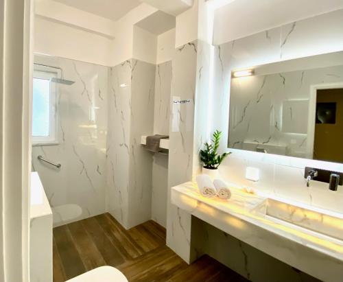 a white bathroom with a sink and a mirror at Athenian Condo in Athens