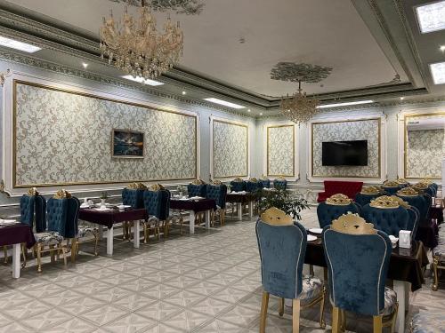 una sala da pranzo con tavoli e sedie e un lampadario di HOTEL ALMAZ PLAZA a Yakkasaray
