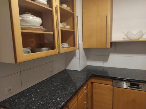 une cuisine avec des armoires en bois et un comptoir noir dans l'établissement Sankt Goar, Schöne und einladende Ferienwohnung, à Sankt Goar