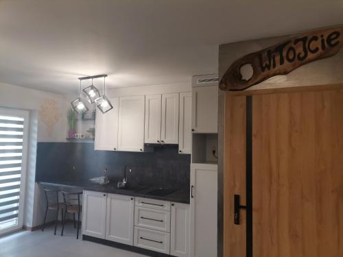 a kitchen with white cabinets and a black counter top at Apartament Górska Szarotka in Nowy Targ