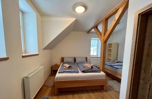 a small bedroom with a bed and two windows at Chata Hubertka Krkonoše in Vítkovice