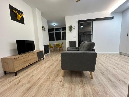 a living room with a chair and a flat screen tv at Industrial -Apartamentos Birdie- in Albacete